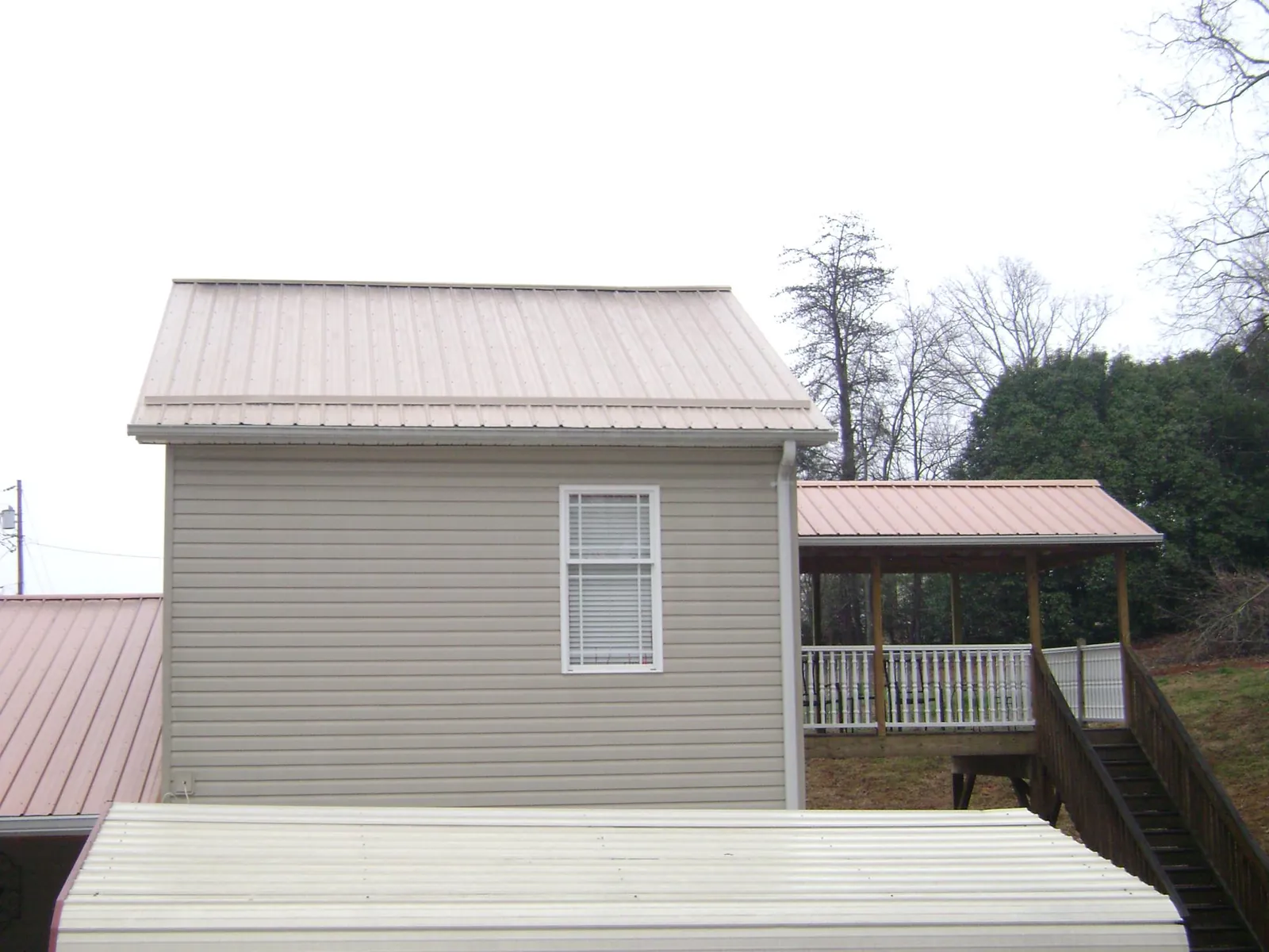 Tan metal roofs on a two story addition and attached porch, from a Roof Replacement job in Vienna
